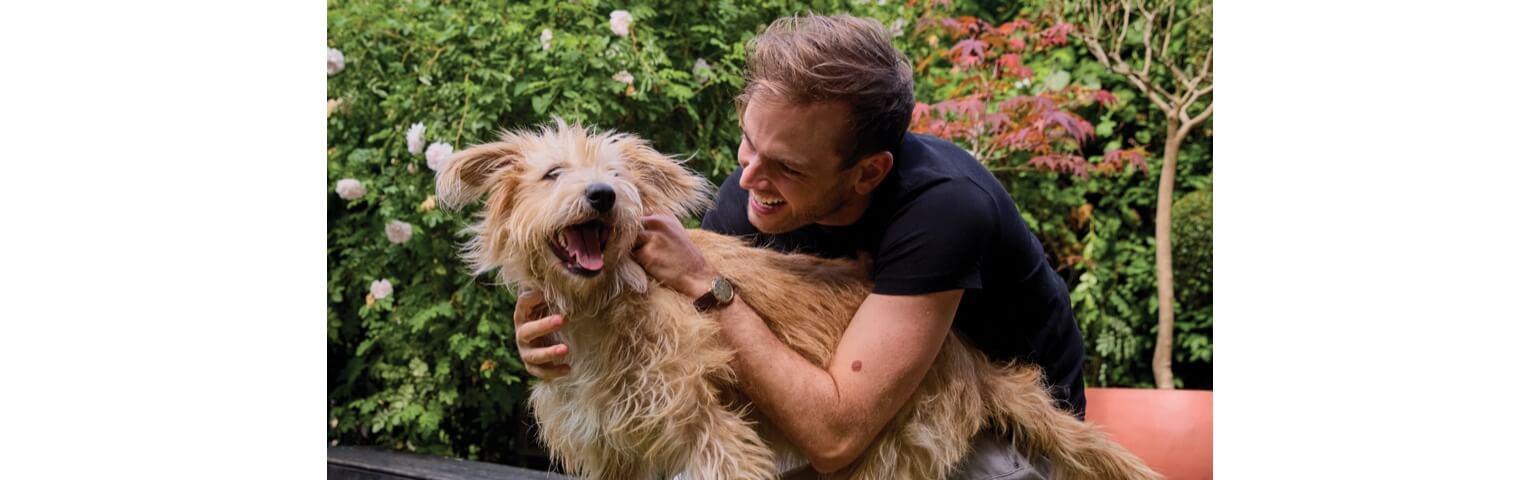 Rory the Vet hugging a happy dog in a garden.