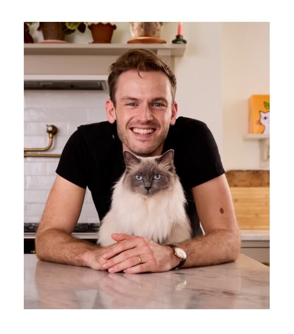 Rory the vet in a black shirt with a Ragdoll cat on a kitchen counter.