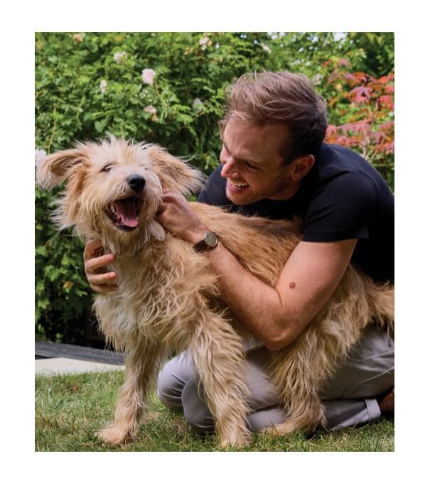 Rory the Vet hugging a happy dog in a garden.